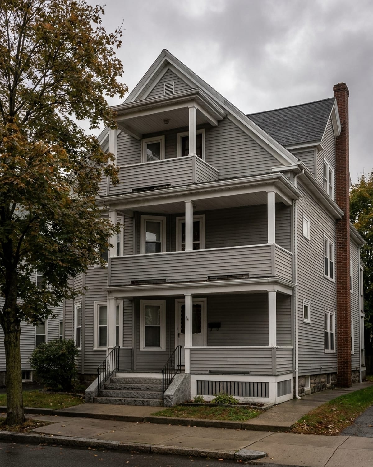 A street of triple deckers and colonial houses lined with maple trees in early autumn.